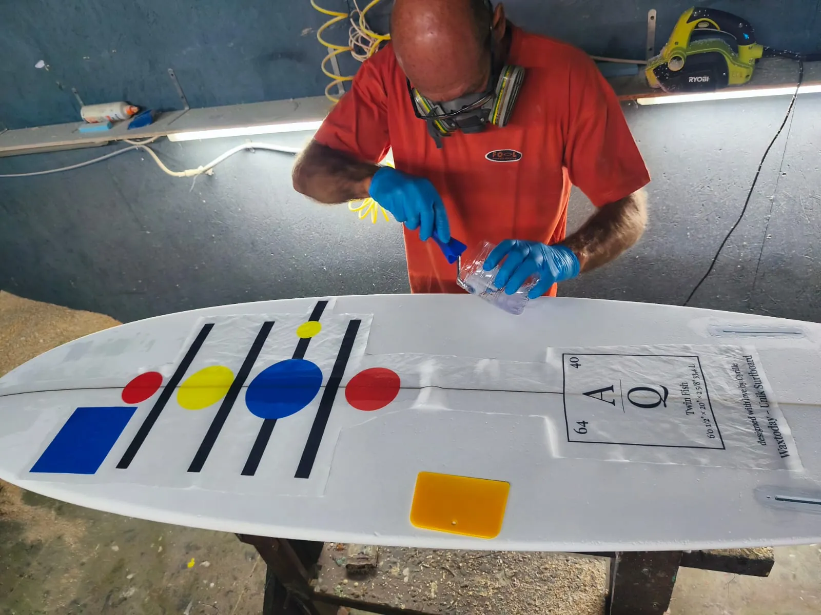Laurent, le shaper, intègre le visuel imprimé sur fibre de soie lors de la stratification